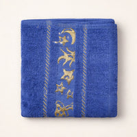 Blue kids towel with gold star and moon embroidery, folded on a light background.