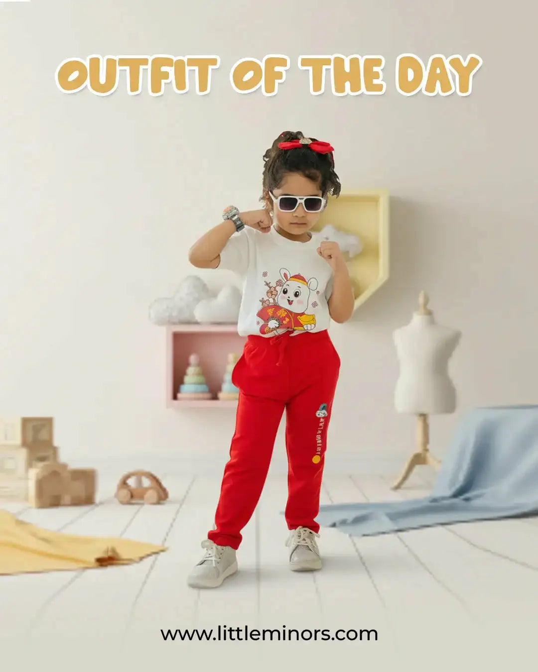 Girl in white bear print t-shirt and red pants posing in stylish kids room, trendy baby clothes